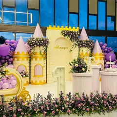 The complete setup for a magical princess party, featuring a custom castle, a royal carriage for photos, and beautiful floral arrangements in shades of purple.