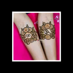 The arm design for this engagement mehendi features lovely floral wreaths with the couple's initials and interlocking rings.