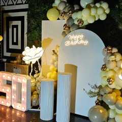 A detailed look at the 50th birthday decor, focusing on the arched backdrop, neon sign, and the tasteful balloon garland in a muted color palette with gold accents.