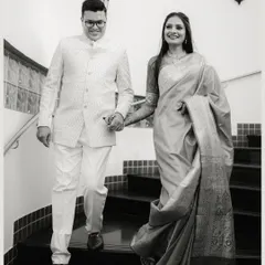 A classic black and white photograph of a couple descending a staircase, holding hands. The elegant composition and their formal attire give this shot a timeless, graceful feel.