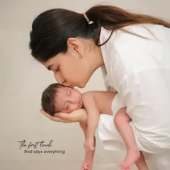 This pose is perfect for showing just how small and delicate a newborn is. The mother's gentle kiss and the way the baby fits perfectly in her hand create a deeply touching and memorable portrait.