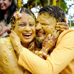A candid shot of a couple laughing and embracing, covered in turmeric paste during their Haldi ceremony. These are the moments of pure joy I strive to create.