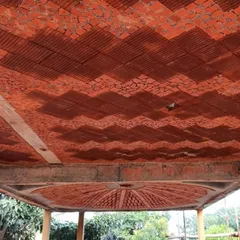 We find beauty in reuse. This ceiling features a mosaic made from broken terracotta tiles, creating a visually stunning pattern while upcycling materials that would otherwise be wasted. The design includes a brick dome for a fan.