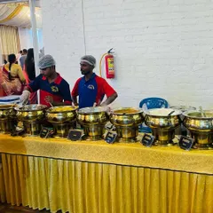 Our staff ready to serve at a wedding buffet. We offer a mix of veg and non-veg dishes, clearly labeled, so guests can choose according to their preference. The golden serving bowls add a touch of elegance.