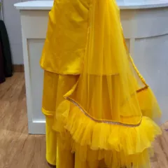 The back view of the custom yellow tiered skirt for a Haldi ceremony outfit. The layers of fabric create beautiful movement, and the net dupatta adds a touch of grace to the ensemble.