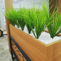 I use high-quality artificial plants that look incredibly realistic. This close-up shows the vibrant green grass used in the restaurant planters, set in a bed of clean white pebbles for a crisp, maintenance-free finish.