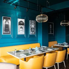 Bold color choices, like this vibrant yellow seating against a deep blue wall, inject energy and modernity into the restaurant's classic framework. This approach creates distinct zones and moods within the same establishment.