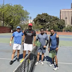 Players posing for a photo at the net during the Ad In Tennis Open at Modern School. Our events are a great way to meet fellow tennis enthusiasts.