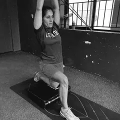 A black and white photo of a client performing a challenging lunge variation, capturing their focus and strength.