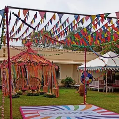 A full-blown carnival theme for a fun and colorful Mehendi party. This outdoor setup includes a decorated tent for the couple, a custom dance floor, and vibrant bunting flags.