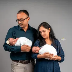 A tender moment as new parents each hold one of their newborn twins. This pose beautifully captures the beginning of their journey as a family of four, highlighting the individual bond with each baby.