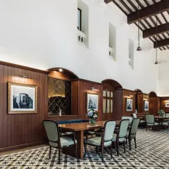 For the historic Bangalore Club, we focused on restoring its colonial grandeur while updating it for modern use. This dining area features high ceilings with exposed wooden beams, classic wood-paneled walls, and custom patterned floor tiles that honor the club's 150-year legacy.