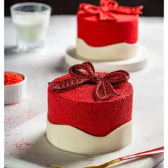 A vibrant red velvet mini-cake shaped like a gift box, showcasing a unique texture and design perfect for festive or romantic campaigns.