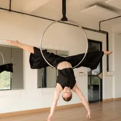 A moment of stillness on the aerial hoop, or lyra. This pose, a variation of a split, showcases the blend of artistry and athleticism that makes this apparatus so captivating. It’s a beautiful example of aerial performance photography.