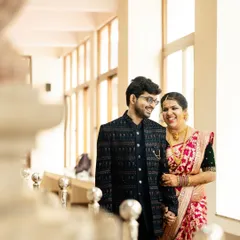 A beautiful, light-filled photo of a couple during their Nischithartha. Dressed in traditional outfits, they share a happy moment in a bright, airy corridor, marking the 'Beginning of Forever'.