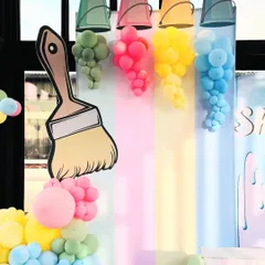 A close-up of the art party's main decor, showing the clever use of balloons to look like paint spilling from buckets. The large paintbrush prop adds a fun, oversized element to the creative theme.