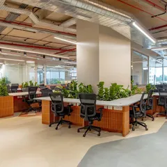 We use biophilic design to enhance the work environment. These workstations are integrated with large planters, bringing nature indoors to improve air quality and employee well-being, while the open layout encourages easy communication.