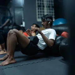 Another angle on the dumbbell hip thrust, showing focus and proper form. We use a variety of tools, including heavy bags, for support during strength exercises.