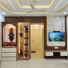 We designed this open-plan living area to be both beautiful and functional for a modern Indian family. The space seamlessly integrates a statement TV unit with fluted panels, a custom-lit pooja mandir, and a compact dining area, all tied together with elegant ceiling lights.