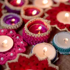 Our handmade crochet diya holders glowing warmly, creating a perfect festive ambiance. This collection includes various designs like beaded coasters and simple jackets, all crafted to make your Diwali celebrations brighter and more personal.