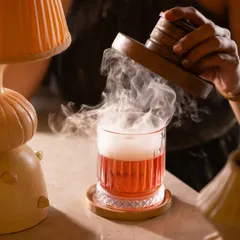 A smoked old fashioned, captured to enhance the moody, sophisticated vibe of the bar. The interaction with the smoke adds a layer of theatre to the image.