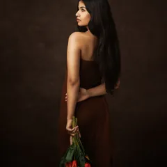 The poetry of presence, captured in light. This pose, with flowers held behind her back, adds a touch of mystery and romance to the portrait.
