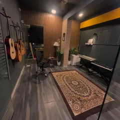 A wider view of our main studio room, showing the keyboard setup, wall-mounted guitars, and ample space for lessons and practice.