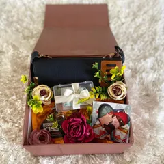 A stylish and thoughtful gift box for her. This hamper features a chic black handbag, Hershey's Kisses, and other small, curated items, making it a wonderful surprise for a friend or loved one.