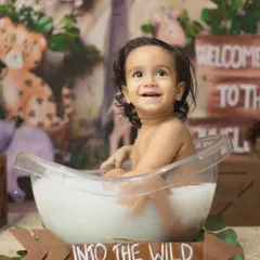 A happy baby boy looks up with a huge smile during his 'Into the Wild' milk bath photoshoot.