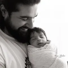 Daddy's boy. This black and white shot beautifully captures the tender bond between a father and his newborn son, a moment of pure love and protection.