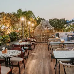 The rooftop terrace is designed as a lush oasis, with dense foliage, wooden decking, and unique woven seating pods. It offers a complete escape, blending the feeling of a garden with the energy of a city bar.
