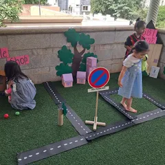 Children interact with different parts of the community, including a vegetable shop and road signs. This detailed setup encourages complex narratives and social interactions.