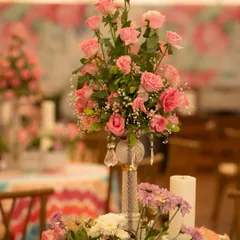 A tall, elegant centerpiece of pink roses set in a crystal-accented vase. This classic arrangement adds a touch of sophistication to the colorful, patterned tablecloth.