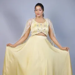 This pastel yellow lehenga is designed to bring a ray of sunshine to any event. The simple, flowing satin skirt is paired with a beautifully embroidered blouse and two sheer back drapes, creating an ethereal and modern look.