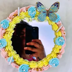 A unique selfie mirror cake. The center of the cake is a real mirror, framed with colorful frosting and a beautiful butterfly, making it a fun and interactive dessert.