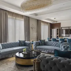 This grand living and dining space features our custom-made tufted sofas in a cool blue. We designed the seating to be both elegant and ample, perfect for hosting large gatherings in this luxurious villa.