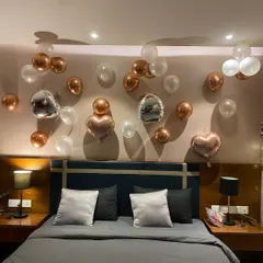 A close-up of the balloon arrangement over the headboard. This shows the detail in the placement of the rose gold, white, and unique silver disco ball style balloons for a fun yet elegant birthday decoration.