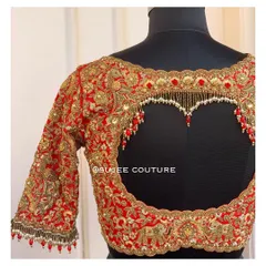 A showcase of one of my signature statement back designs. This vibrant red bridal blouse features a dramatic heart-shaped keyhole cutout, heavily embellished with zardozi work and delicate pearl tassels for a truly memorable look.
