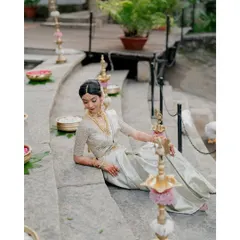 A serene portrait of the bride, seated amidst traditional decor elements like stone steps and brass lamps, embodying timeless elegance.