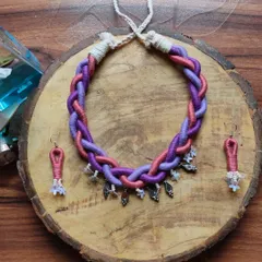 I created this braided thread necklace for a modern, boho look. The shades of purple and pink are woven together and accented with small silver charms, and it comes with matching earrings.