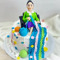 A cake for a mom who loves knitting, ordered by her son for her leap year birthday. The design features an edible caricature and colorful balls of yarn.