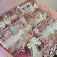 A peek inside the acrylic boxes, revealing beautifully wrapped gifts including a Moschino baby item, all tied with satin bows.