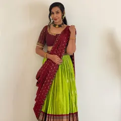 A classic langa voni or half saree in a vibrant lime green and maroon combination. This traditional outfit is perfect for festivals and family functions, designed to be both beautiful and comfortable. The blouse features delicate handwork on the sleeves.