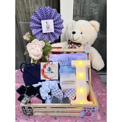 A beautiful birthday hamper for her, complete with a large teddy bear, a light-up initial 'I', and a collection of accessories and treats, all arranged in a rustic wooden tray.