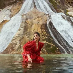 An ethereal shot from our editorial collaboration with Femina Miss India in Arunachal Pradesh. The model's hair is styled to flow naturally, complementing the dramatic red gown and the powerful waterfall backdrop for a high-fashion, camera-ready look.