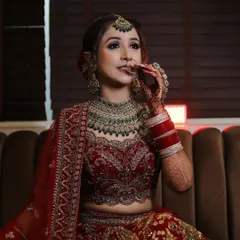 A beautiful bride ready for her wedding. This look includes detailed eye makeup, a perfectly matching lip color, and traditional jewelry, all complementing her stunning red lehenga.