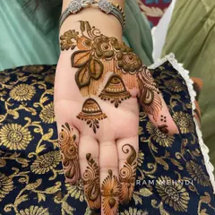 A stylish back-of-hand design with floral motifs and hanging jhumka elements. The patterns on the fingers complete this chic, jewellery-inspired look.
