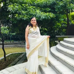A full look of the client in her beautiful white Kasavu saree, paired with the custom purple blouse and traditional gold jewelry.