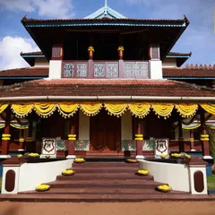 Decorating a 75-year-old heritage home in Kerala, with traditional marigold garlands accentuating the beautiful architecture under a clear blue sky.