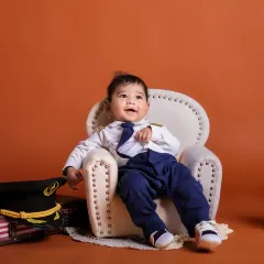 Our little captain is ready for his flight. The pilot theme, complete with a uniform and mini armchair, is a fantastic choice for an imaginative baby photoshoot.
